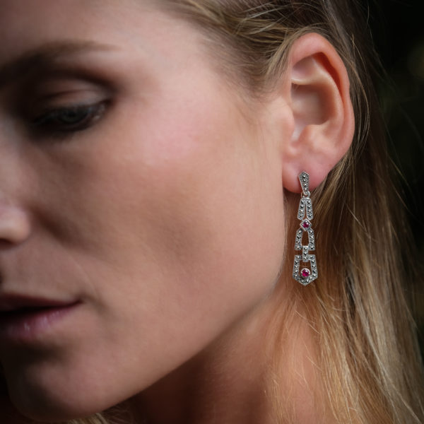 boucles d'oreilles art déco argent et rubis portées sur l'oreille gauche d'une femme.