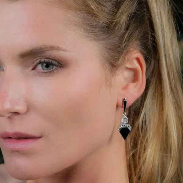 Boucles d'oreilles pendantes art déco en argent onyx et marcassite de forme triangulaire portée par une mannequin.