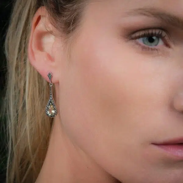 Boucles d'oreilles art déco en argent et quartz lemon portées en plan serré.