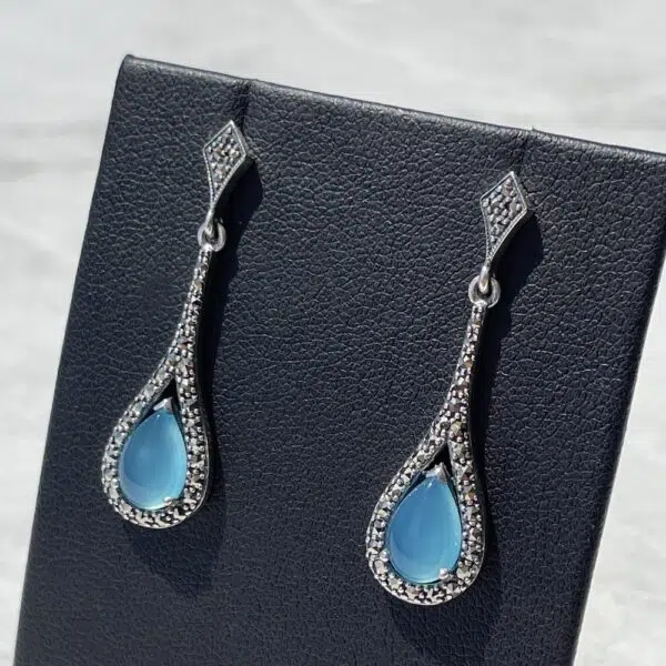 art deco silver and blue topaz earrings set on a grey background