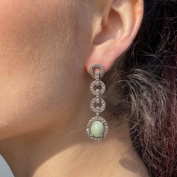 Boucles d'oreilles en argent pendantes sertis de jade vert et de marcassite sur l'oreille gauche d'une mannequin