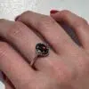 Bague argent et grenat style ancien est portée sur le majeur de la main droite.