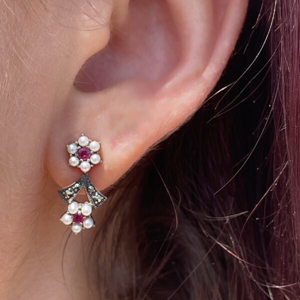 Boucles d'oreilles rubis perles et argent portées par un modèle sur l'oreille gauche.