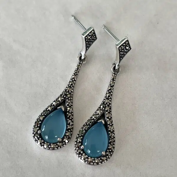 art deco silver and blue topaz earrings set on a grey background