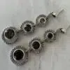 Boucles d'oreilles pendantes avec trois pierres de quartz fumé posées sur une table blanche