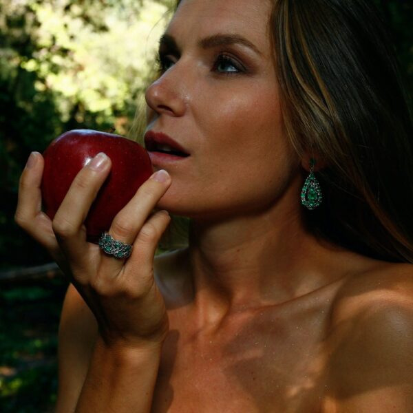 boucles d'oreille et bague vintage portées par une mannequin de profil mangeant une pomme dans les bois.