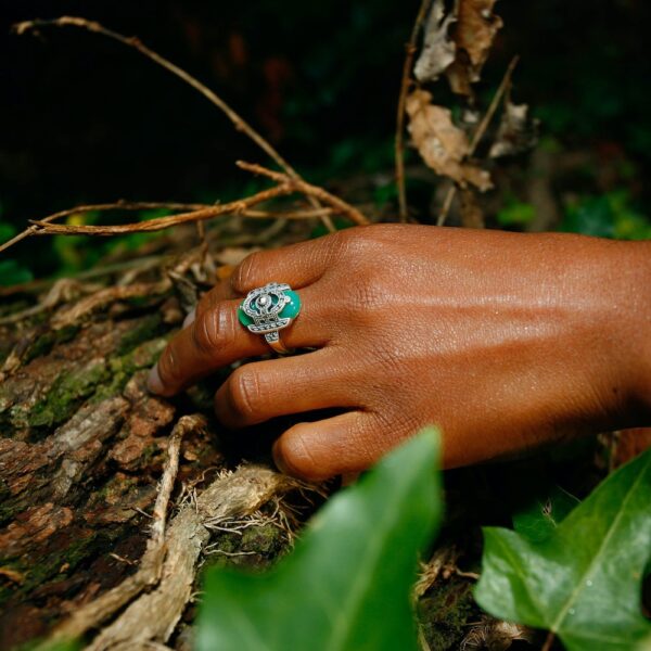 Bague art déco vintage en argent et agathe verte portée sur la main gauche d'une mannequin dans les bois.